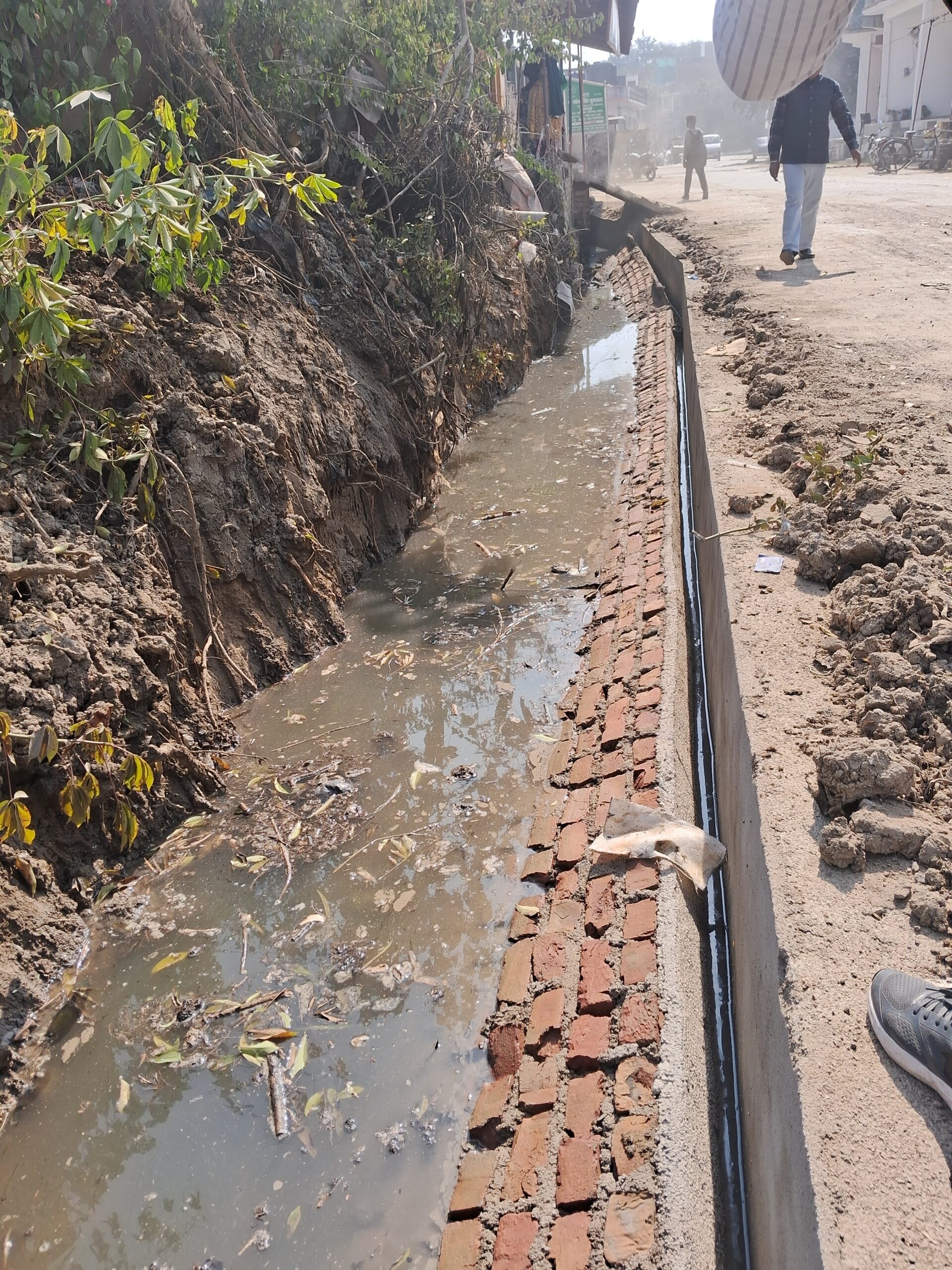 जालौन के कोंच में निर्माणाधीन नाले की ढही हुई दीवार और घटिया निर्माण सामग्री का दृश्य।