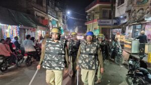 कोंच नगर की सड़कों पर भारी पीएसी बल के साथ पैदल मार्च करते क्षेत्राधिकारी और कोतवाली पुलिस।