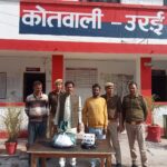 जालौन पुलिस की गिरफ्त में खड़े तीन गांजा तस्कर, मेज पर बरामद गांजा, नकदी, मोबाइल और पीछे खड़ी सफेद स्कॉर्पियो कार