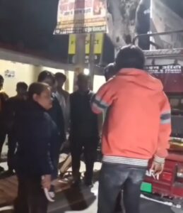 उरई के जिला परिषद परिसर के पास बीच सड़क पर एक युवती युवक की चप्पल से पिटाई करते हुए, पास में खड़ी भीड़ और वायरल वीडियो का एक दृश्य।