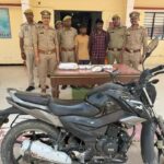 जालौन पुलिस की गिरफ्त में खड़े दो शातिर अंतरजनपदीय चोर, सामने मेज पर बरामद नकद राशि, जेवरात और मोबाइल फोन रखे हुए हैं