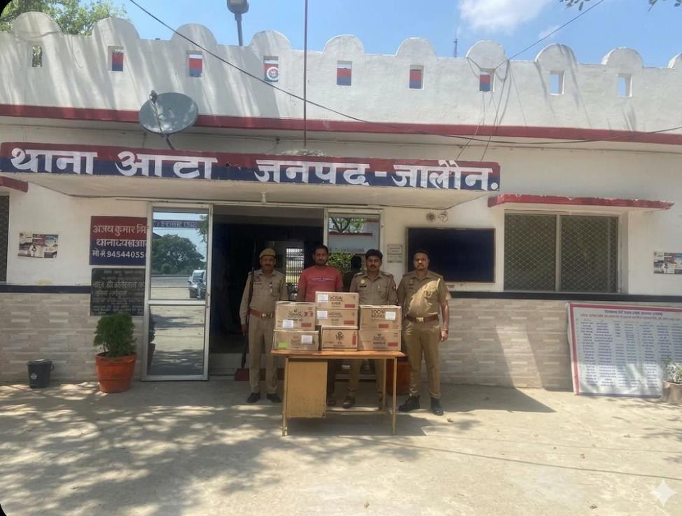 जालौन के थाना आटा पुलिस और आबकारी विभाग की संयुक्त टीम द्वारा पकड़ी गई अवैध अंग्रेजी शराब की पेटियों के साथ गिरफ्तार आरोपी सरमन यादव और पुलिसकर्मी