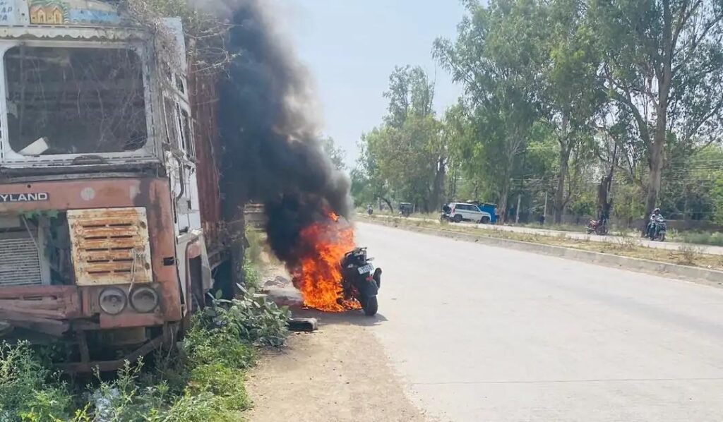 जालौन के उरई में कालपी रोड पर धू-धू कर जलती हुई बाइक और बचाव कार्य में जुटे पुलिसकर्मी एवं स्थानीय लोग