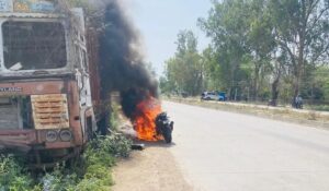 जालौन के उरई में कालपी रोड पर धू-धू कर जलती हुई बाइक और बचाव कार्य में जुटे पुलिसकर्मी एवं स्थानीय लोग