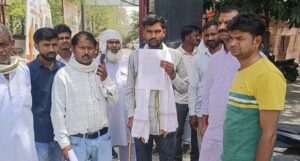 बरहल गांव उरई में पीड़ित का घर, टूटी अलमारी और ताले के साथ घटनास्थल का दृश्य, आसपास खड़े ग्रामीण और जांच करती पुलिस