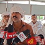धमनी गांव के खेत में पुलिस और ग्रामीणों की मौजूदगी, पेड़ के पास खड़ा शोकाकुल परिवार, किसान की आत्महत्या के बाद का दृश्य
