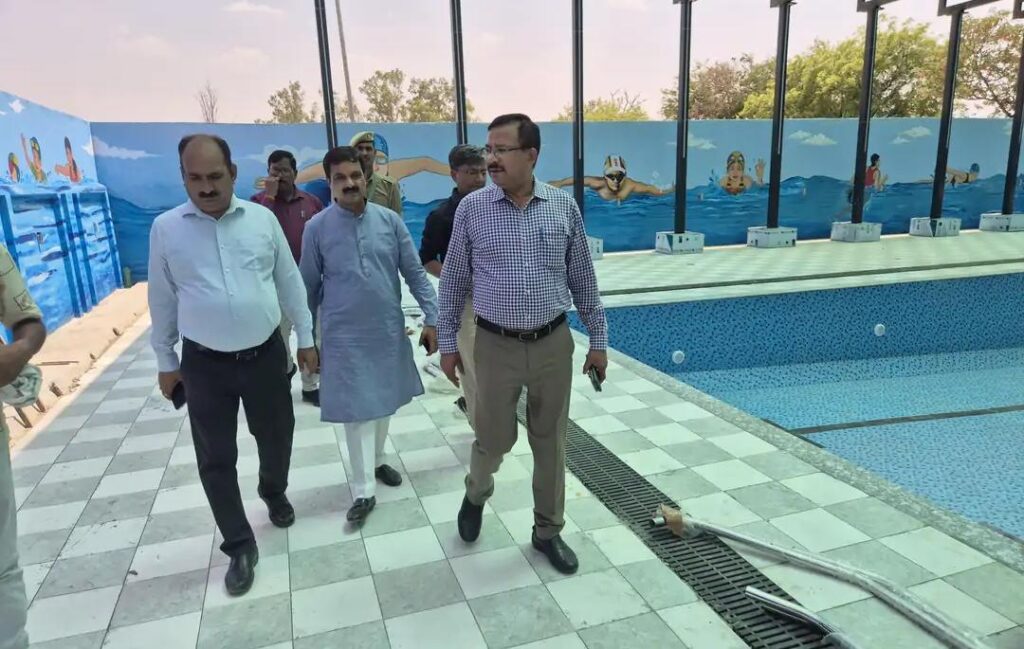Jalaun News, Orai News, Indira Stadium Orai, Swimming Pool Orai, DM Rajesh Kumar Pandey, UP Sports News, Jalaun Sports, Swimming Pool Inauguration, Uttar Pradesh News, Jalaun Administration, Jal Shakti Mantri Nidhi, Youth Development, Sports Infrastructure, Orai Updates, Jalaun District, Hindi News, UP Samvad, जालौन समाचार, उरई न्यूज़, इंदिरा स्टेडियम, तैराकी प्रतियोगिता, खेल विकास, उत्तर प्रदेश खेल, जिलाधिकारी जालौन, स्थानीय खेल सुविधाएंजालौन के उरई स्थित इंदिरा स्टेडियम में नवनिर्मित आधुनिक तरणताल का निरीक्षण करते जिलाधिकारी राजेश कुमार पाण्डेय और प्रशासनिक अधिकारी