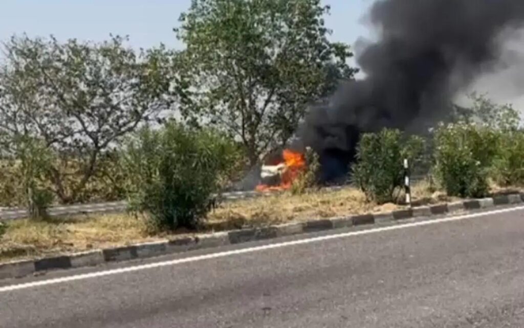 जालौन के नेशनल हाईवे 27 पर पिरौना के पास धूँ-धूँ कर जलती हुई सफेद रंग की कार और मौके पर मौजूद पुलिस बल