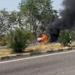 जालौन के नेशनल हाईवे 27 पर पिरौना के पास धूँ-धूँ कर जलती हुई सफेद रंग की कार और मौके पर मौजूद पुलिस बल