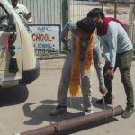 जालौन के कोंच में मुख्य मार्ग पर कार के ऊपर गिरा टूटा हुआ जर्जर बिजली का पोल, क्षतिग्रस्त कार और आस-पास जमा भीड़ का दृश्य