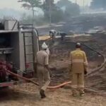 जालौन के डकोर में हमीरपुर शाखा नहर के पास खेतों में लगी भीषण आग को बुझाते दमकल कर्मी और स्थानीय ग्रामीण, पृष्ठभूमि में गैस एजेंसी का गोदाम।