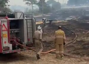 जालौन के डकोर में हमीरपुर शाखा नहर के पास खेतों में लगी भीषण आग को बुझाते दमकल कर्मी और स्थानीय ग्रामीण, पृष्ठभूमि में गैस एजेंसी का गोदाम।