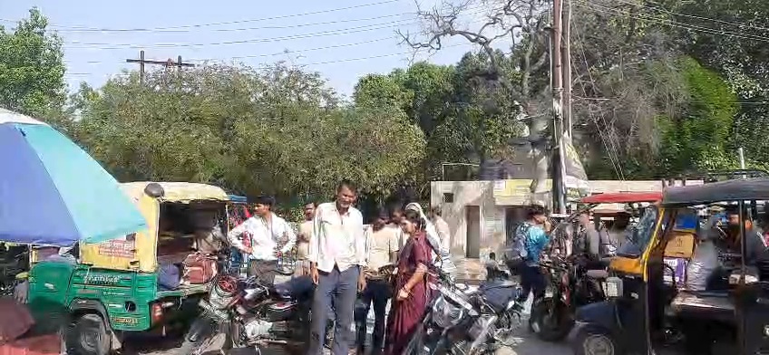 उरई के कालपी बस स्टैंड के पास भीड़भाड़ वाला इलाका, जहाँ पुलिस की टीम जांच कर रही है और पास में एक खड़ा ऑटो रिक्शा दिखाई दे रहा है।