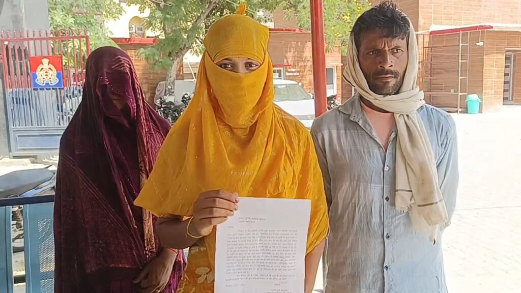 जालौन में एसपी कार्यालय के बाहर खड़ी न्याय की गुहार लगाती व्यथित रेप पीड़िता और उसका परिवार, बैकग्राउंड में पुलिस मुख्यालय की झलक