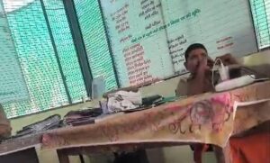 उरई की गल्ला मंडी पुलिस चौकी में कुर्सी पर बैठकर मेज (टेबल) पर पैर रखे हुए चौकी इंचार्ज अमित चतुर्वेदी, और सामने अपनी शिकायत लेकर खड़ी असहाय फरियादी महिलाएं