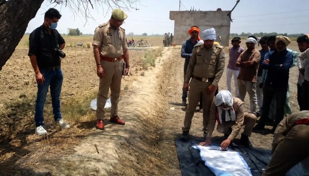 जालौन के कुठौंद क्षेत्र के मदारीपुर गांव के बाहर पेड़ से लटका शव, घटनास्थल पर जांच करती कुठौंद थाना पुलिस और एकत्र ग्रामीणों की भीड़।