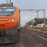 आंधी-तूफान का बड़ा असर: जालौन में 7 घंटे तक आटा स्टेशन पर खड़ी रही अमृत भारत एक्सप्रेस, यात्रियों ने झेली भारी परेशानी आटा रेलवे स्टेशन पर कई घंटों तक खड़ी अमृत भारत एक्सप्रेस के बाहर और प्लेटफॉर्म पर इंतजार करते यात्री, आंधी-तूफान के बाद बाधित रेल संचालन का दृश्य।