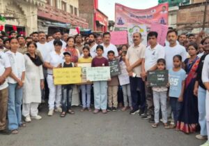 उरई के टाउन हॉल परिसर में 12वें अंतर्राष्ट्रीय योग दिवस की पूर्व संध्या पर आयोजित भव्य जन-जागरूकता रैली को हरी झंडी दिखाकर रवाना करते सदर विधायक गौरी शंकर वर्मा, जिलाधिकारी राजेश कुमार पांडेय और सीडीओ के.के. सिंह। पृष्ठभूमि में हाथों में बैनर और तख्तियां लिए हजारों उत्साही प्रतिभागी।