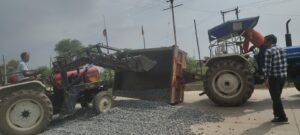 जालौन-उरई स्टेट हाईवे पर गिट्टी से भरी ट्रैक्टर ट्रॉली पलटने के बाद सड़क पर बिखरी गिट्टी और बाधित यातायात का दृश्य।