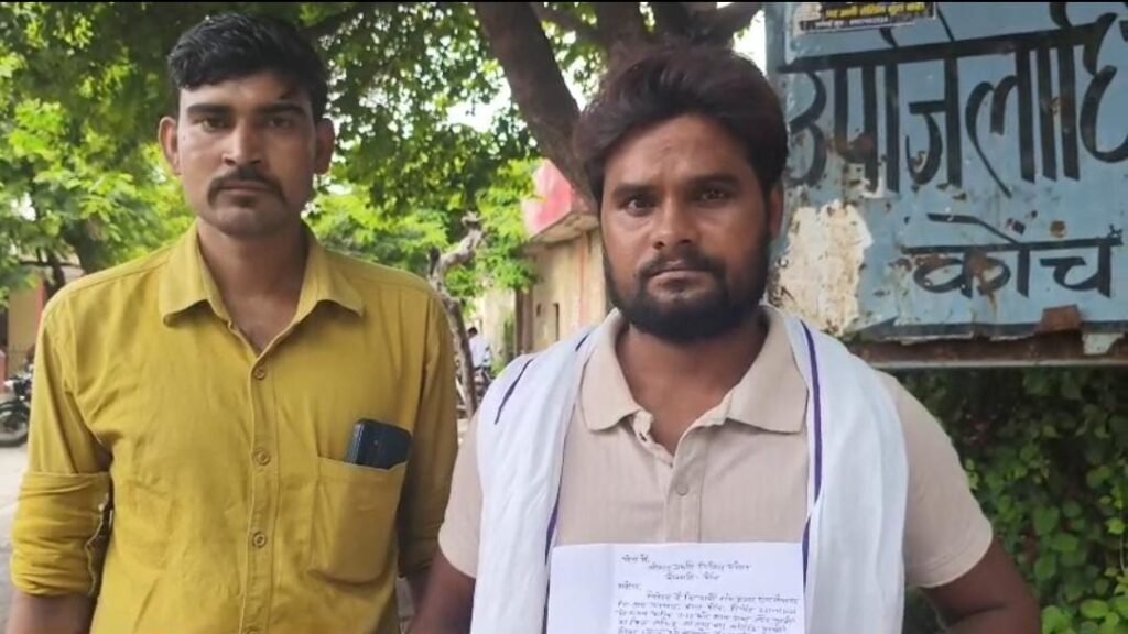 जालौन के कोंच विद्युत विभाग कार्यालय के बाहर हंगामा करते हुए पीड़ित युवक और एकत्रित स्थानीय लोग, जहाँ सुरक्षाकर्मी और पुलिस बल भी मौजूद है।