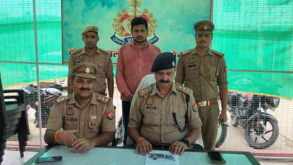 जालौन कोतवाली पुलिस द्वारा गिरफ्तार किए गए आरोपी शिवम चौधरी को मीडिया के सामने पेश करते हुए या पुलिस हिरासत में दिखाए जाने का एक सांकेतिक दृश्य, जिसमें पुलिसकर्मी सुरक्षा घेरे में नजर आ रहे हैं।