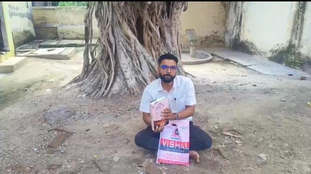 जालौन के नदीगांव में संपूर्ण समाधान दिवस कक्ष के बाहर नगर पालिका अधिनियम की किताब लेकर धरने पर बैठे सभासद अमित कुमार।