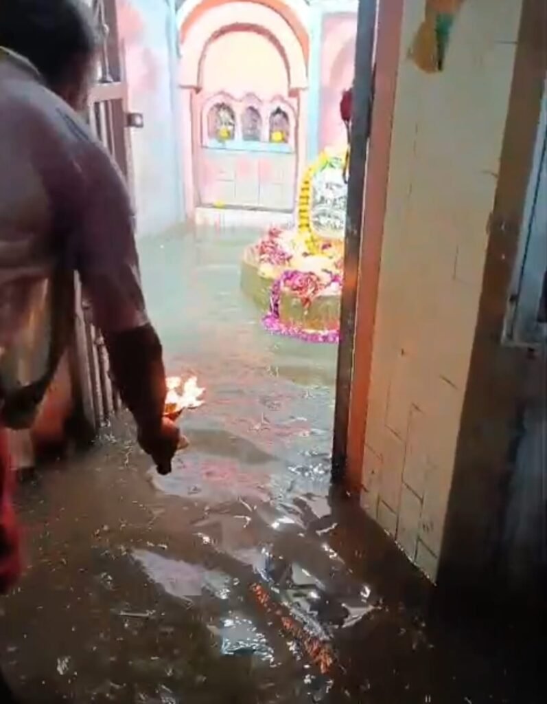 कोंच के प्राचीन भूतेश्वर मंदिर परिसर में बारिश का गंदा पानी भरा, जलभराव के बीच पूजा-अर्चना करते पुजारी