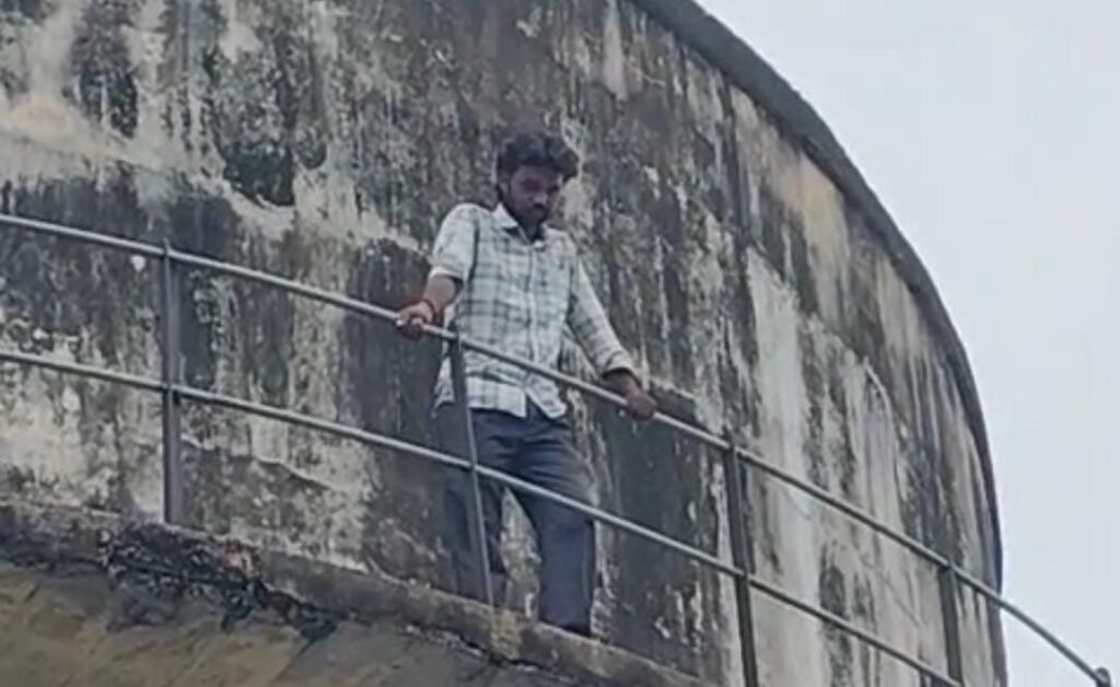 कोंच कोतवाली क्षेत्र के सरोजिनी नायडू पार्क के पास स्थित पानी की टंकी पर पत्नी और दो साल के बच्चे के साथ चढ़ा युवक, नीचे जुटी भीड़ और पुलिस प्रशासन।