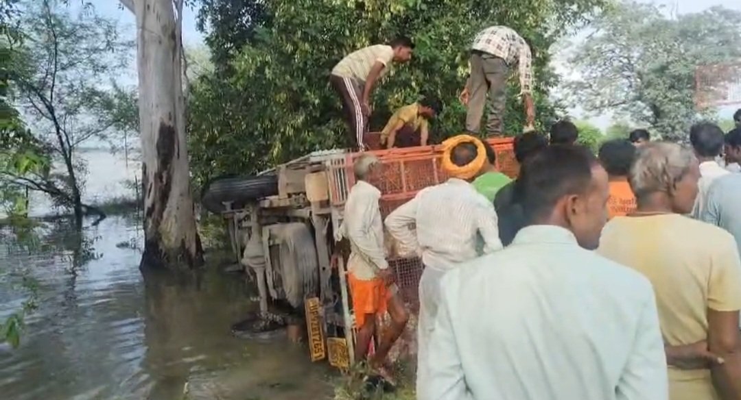 खंती में पलटी लोडर से मुर्गों को निकालते ग्रामीण